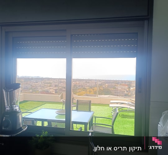 חלון עם תריסים נוף חיצוני שולחן וכיסאות